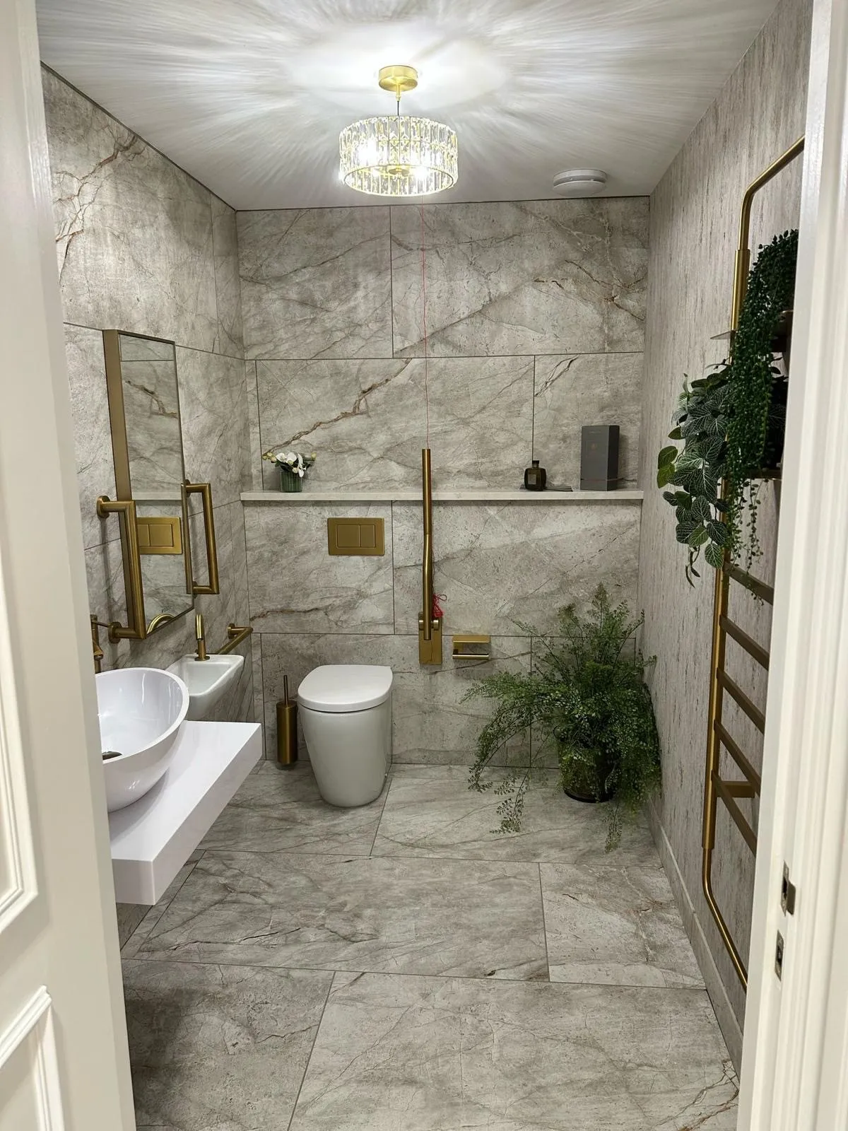 Marble-tiled accessible washroom with brass fittings at Bromsgrove Dental Specialists