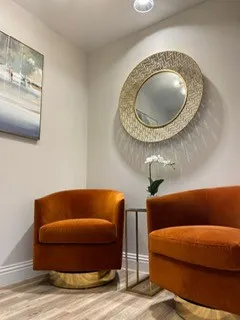 Burnt-orange armchairs beneath a woven mirror at Bright Orthodontics, Liverpool