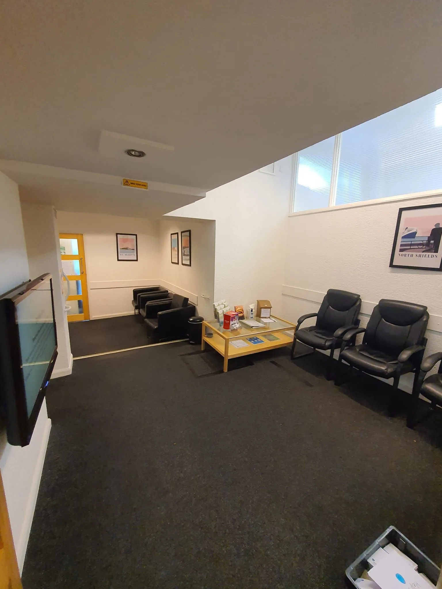 The original waiting room with dark carpet and office chairs before refurbishment