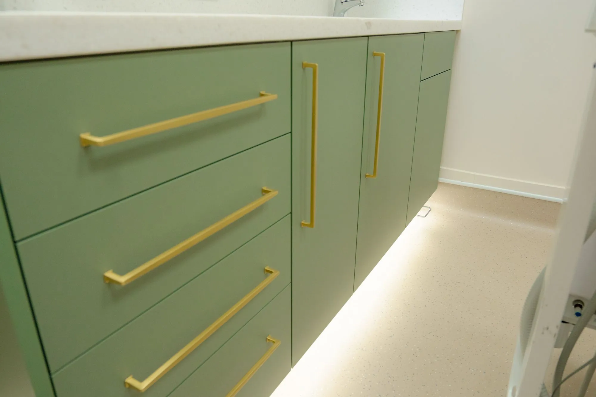 Bespoke sage-green cabinetry with brass handles at Alma Dental, North Shields